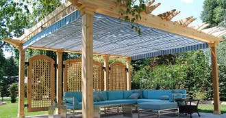 A blue couch under a wooden pergola.