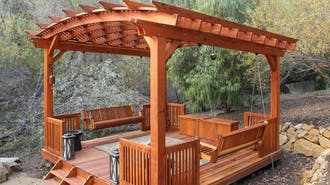 A wooden pergola with swing benches.